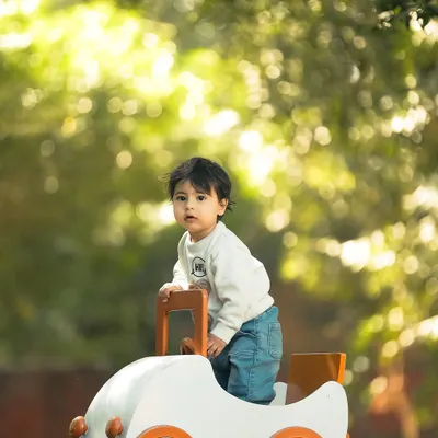 A tiny adventurer on the move. This outdoor portrait uses the beautiful, soft background light, known as bokeh, to make the child and his little toy car pop, creating a magical, sun-drenched image.