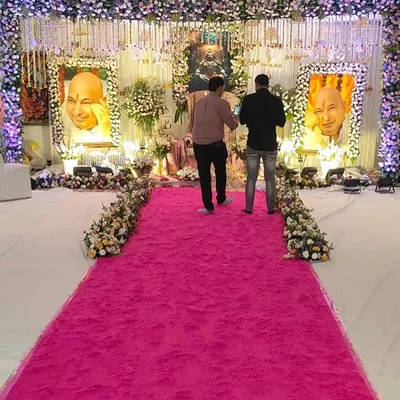 A wide view of a large-scale satsang event I decorated. The grand stage is the focal point, and I used a vibrant pink ruffled carpet for the walkway to create a welcoming path for devotees.