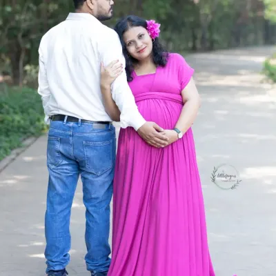 An expecting mother in a vibrant pink gown leans lovingly against her partner. This outdoor maternity portrait captures the quiet strength and connection between parents-to-be.