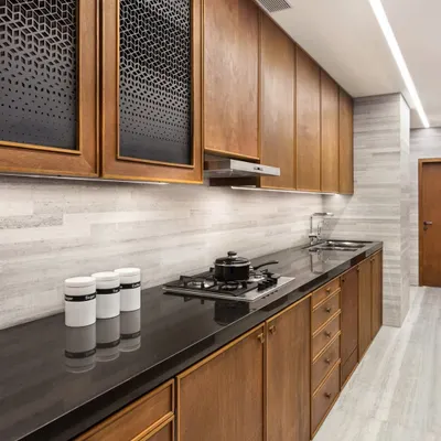 The kitchen in the Limestone Residence features custom cabinetry crafted from teak with a natural linseed oil polish. The perforated cabinet doors add a decorative yet functional detail, while the stone backsplash and countertops provide a durable and elegant surface.
