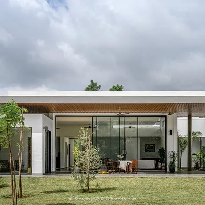 The "Nisarg" residence, where a striking floating slab rests on sleek pilotis, forming a covered leisure space that extends into the lush green landscape. The architecture is deliberately minimal to let nature take center stage.