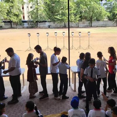 A wide shot of a free workshop conducted at a local school. You can see a long line of students eagerly waiting to try their hand at rifle shooting, showing the immense interest we generate with these outreach programs.