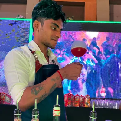 The 'Bubble Pop' cocktail is an interactive experience. Here, our bartender presents the finished drink, where a fragrant smoke bubble sits atop a vibrant red cocktail.