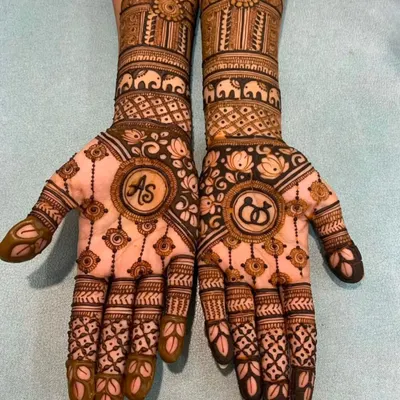 A perfect engagement mehndi design featuring the couple's initials 'AS' on one palm and interlocking rings on the other.