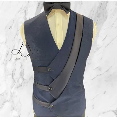 This is not your average waistcoat. The unique asymmetrical design with satin strap details makes it a true statement piece, perfect for layering over a shirt to create a distinctive and modern formal look.