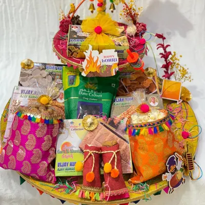 A grand Lohri hamper filled with all the essentials for the celebration. This platter includes packets of 'gajak', 'rewari', dates, and decorated 'potlis' of popcorn, all arranged beautifully.