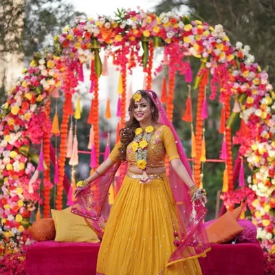 Here is a perfect example of a vibrant Haldi backdrop. I created a full floral arch with a mix of colorful flowers and hanging tassels to frame the bride beautifully, making her the radiant center of attention.
