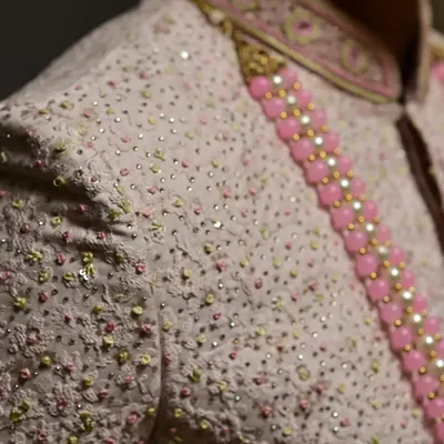 A close-up of the delicate embroidery and sequin work on this elegant pink sherwani.