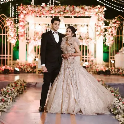 A picture perfect moment for the beautiful couple against the elegant reception stage we designed. The combination of soft florals, warm lighting, and intricate structures created a truly romantic backdrop.