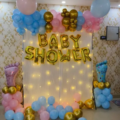 A classic gender reveal baby shower backdrop. This setup includes a fairy light curtain, "BABY SHOWER" foil balloons, and balloon pillars with "It's a Girl" and "It's a Boy" foils, keeping the surprise.