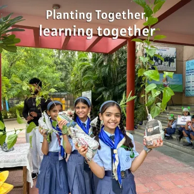 "Planting together, learning together." School students holding saplings they've prepared in newspaper pots. We teach them sustainable nursery techniques from a young age.