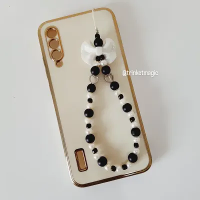 Add a little balance to your bling with this black and white beaded phone strap. It features a cute bow and is attached to a phone, showing how it can elevate your tech.