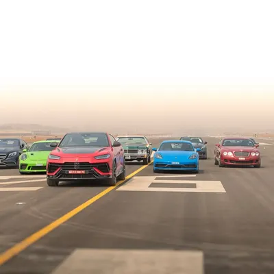A dynamic group shot from the Autocar India airport run, showing a collection of high-performance vehicles moving together on the tarmac.