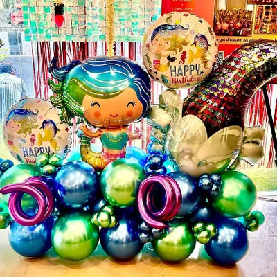 Dive into a magical underwater world with our mermaid-themed balloon bouquet. This arrangement features a beautiful mermaid foil balloon, a shimmering tail, and a sea of blue, green, and purple chrome balloons, perfect for any little ocean dreamer's birthday.