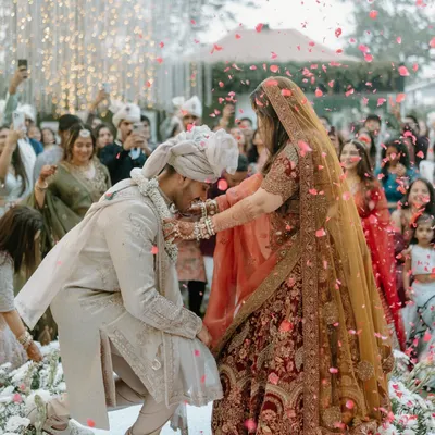 A moment of playful surrender during the jaimala ceremony. The shower of petals and the joyous expressions capture the fun and excitement of this iconic wedding ritual.