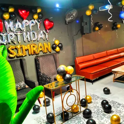 A birthday party setup in a private lounge. I used silver and gold "Happy Birthday" balloons with the name 'Simran', and black and gold accent balloons to match the venue's modern decor.