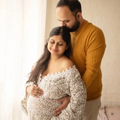 A cozy and intimate portrait of a couple. The soft lace robe and warm lighting create a feeling of comfort and love.