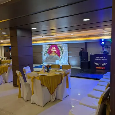 A view of the banquet hall during a Roka ceremony, showing the decorated stage in the background and the guest seating arrangement.