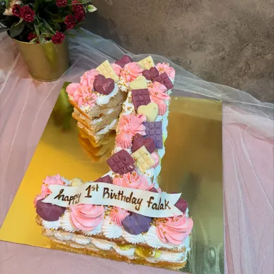 A number "1" monogram cake for a first birthday. This pull apart style cake is decorated with pink and purple frosting and little chocolate bars.