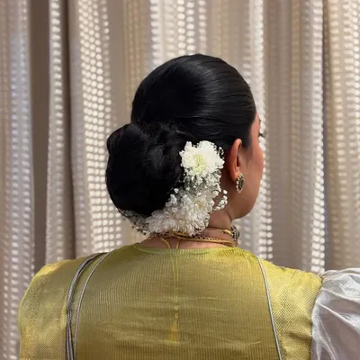 A sleek low bun adorned with a combination of white carnations and baby's breath for a clean, modern look.