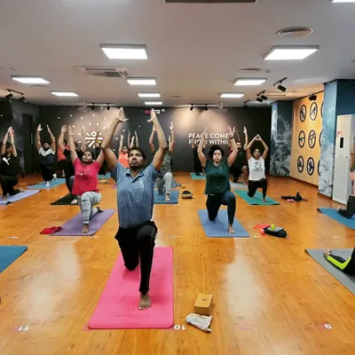 A room full of students lifting their hearts in Anjaneyasana (Low Lunge). This pose is fantastic for opening the hips and chest, and the collective energy makes it even more powerful.