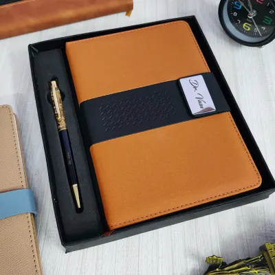 A professional diary and pen set. The tan and black faux-leather diary has a metal plate engraved with "Dr. Vivan", and it comes with a matching premium pen in a gift box.