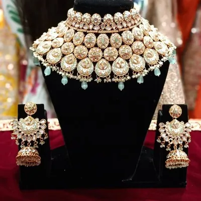 A beautiful Polki and Kundan choker set with matching jhumkas. The light mint green bead drops add a modern touch to this traditional design.