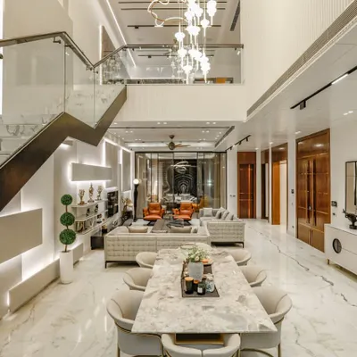 An expansive view of the open-plan living and dining area in our Vikaspuri project. The double-height space, marble flooring, and grand staircase create a breathtaking sense of scale and luxury.