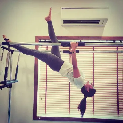 Hanging exercises on the Cadillac are excellent for spinal decompression and building serious core and upper body strength. This pose requires a high level of control and flexibility.