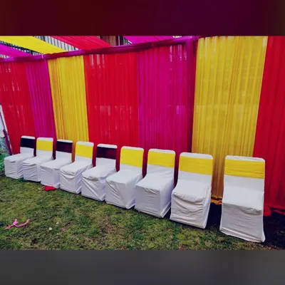 A colorful setup for a Mehendi night or Sangeet. We used a vibrant red and yellow fabric backdrop and arranged chairs with white covers and yellow sashes to create a festive and traditional look for the private celebration.