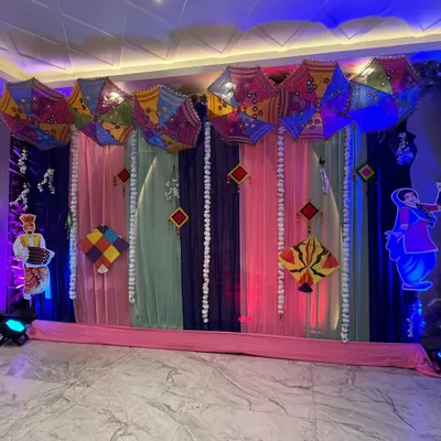 A vibrant stage setup for a Lohri celebration. We used colorful drapes, traditional Punjabi umbrellas (phulkari), kites, and character cutouts to create a festive atmosphere.