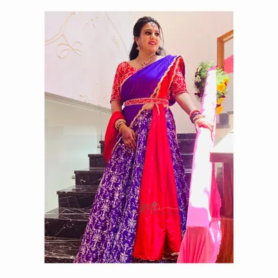Our client looks absolutely stunning in this custom red and purple half-saree. The outfit features a heavily embroidered red blouse and a rich purple brocade skirt.