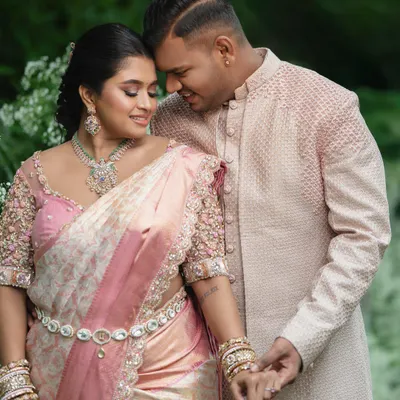 A beautiful moment between this engaged couple. Her pastel pink saree with a 3D floral blouse is perfectly complemented by his elegant pink sherwani.
