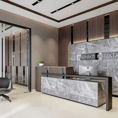 A powerful and modern office reception featuring a grey marble desk and matching accent wall with a bold company logo. The design uses dark wood slats and glass partitions to create a sophisticated and professional corporate entrance.