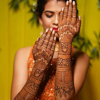 A beautiful bride posing with her mehndi. The design features traditional Indian motifs with delicate floral work, and the rich orange stain shows the quality of my henna.