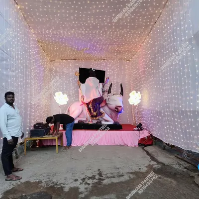 A beautiful pandal setup for the Ganapati festival, featuring a large idol and a backdrop illuminated with strings of fairy lights.