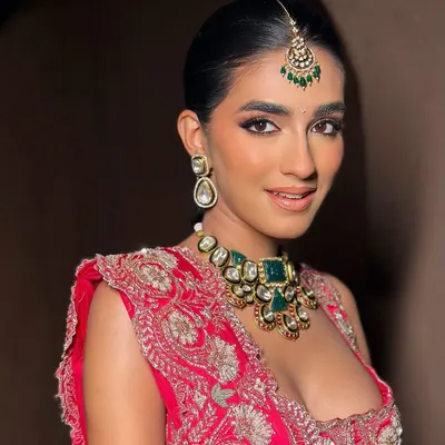 A close-up of a modern bride in a bold red lehenga. The makeup features softly sculpted eyes and glowing skin, creating a look that is both elegant and striking, perfect for a royal-inspired wedding.