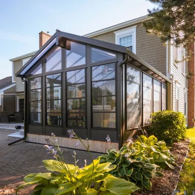 A beautiful example of a gable-roof sunroom addition that complements the existing home's architecture. The floor-to-ceiling glass panels and durable frame create a spacious, all-season room for family enjoyment.