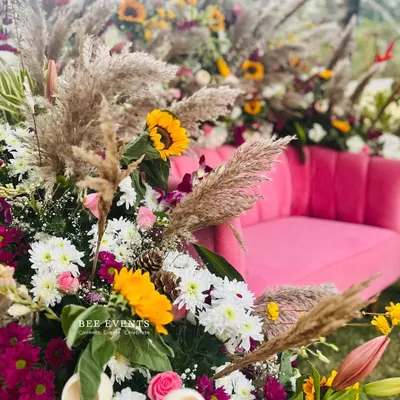 Detailing is everything in modern decor. This Mehendi setup combines a bold pink sofa with pampas grass, sunflowers, and other wildflowers to create a vibrant, bohemian look.