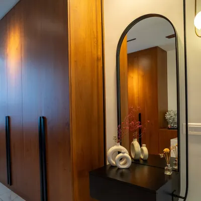A close-up of a veneer-finished wardrobe with long, statement black handles, paired with a custom-designed floating dressing console.