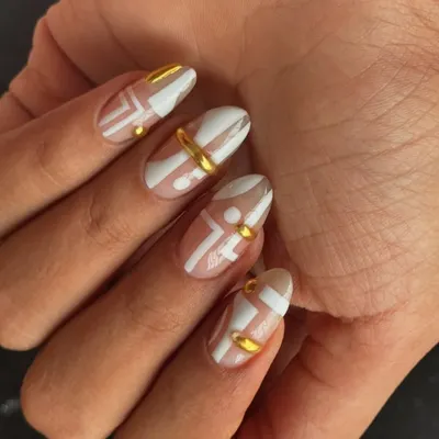 A modern and chic design featuring abstract white patterns on a nude base, accented with 3D gold rings and studs.