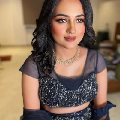 An elegant and modern reception look featuring a navy blue lehenga. The makeup is soft and glamorous with a neutral lip, paired with crimped waves for a chic hairstyle.