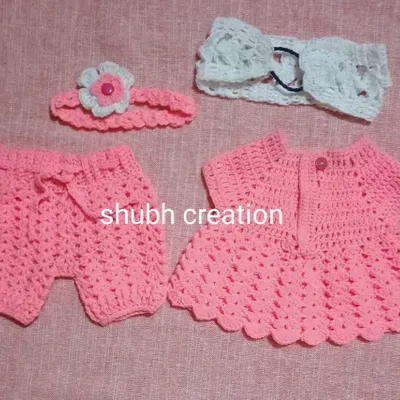 A complete outfit for a baby girl, this set includes a pink crochet dress, matching shorts, and two different handmade headbands for a coordinated look.