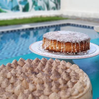 A beautiful display of our cakes by the poolside. This image features a classic glazed cake and a rich tiramisu, showcasing our ability to create delicious desserts that are perfect for any celebration.