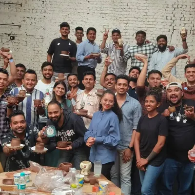 The entire team from a corporate workshop proudly holds up their creations. Our events are a fantastic team-building activity, fostering collaboration and creativity outside the office.