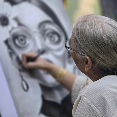 An artist at work. This image captures the intense focus required for charcoal portraiture as a student adds finishing touches to the eye, bringing the character to life.