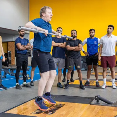 An instructor demonstrates a weightlifting movement during a UKSCA course. Our workshops provide hands-on learning with expert trainers.