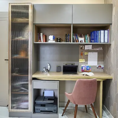 A compact and efficient study nook. The design includes open shelves for books, a corkboard for notes, and a drawer for stationery. The fluted glass cabinet on the side adds a stylish touch while providing concealed storage.
