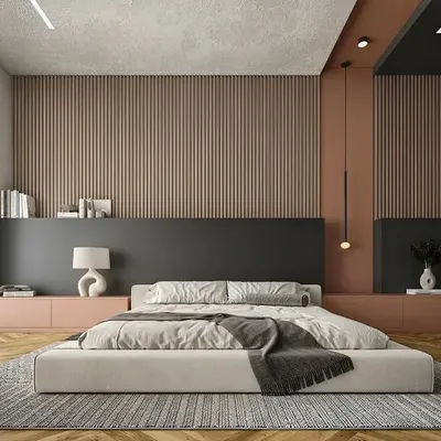 A minimalist bedroom design featuring a low-profile bed and a striking paneled accent wall. The combination of soft pink, deep charcoal, and wood textures creates a calming and contemporary atmosphere.
