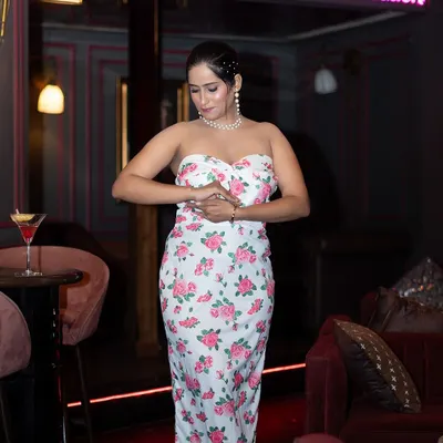 A lifestyle fashion shoot in a stylish cafe. The ambient lighting and location add a layer of sophistication to this shot of a model in a floral dress.